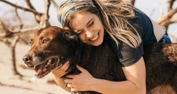 Lady smiling and hugging her brown dog