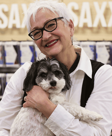 The cutest chocolate Havapoo puppy walking through a field of flowers.